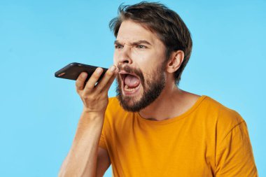  Ağzı açık bir adam elinde bir cep telefonu tutuyor.