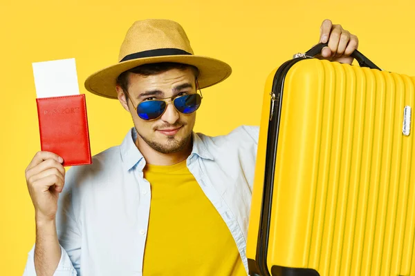 Un hombre con una maleta amarilla y gafas de pasaporte rojas — Foto de Stock