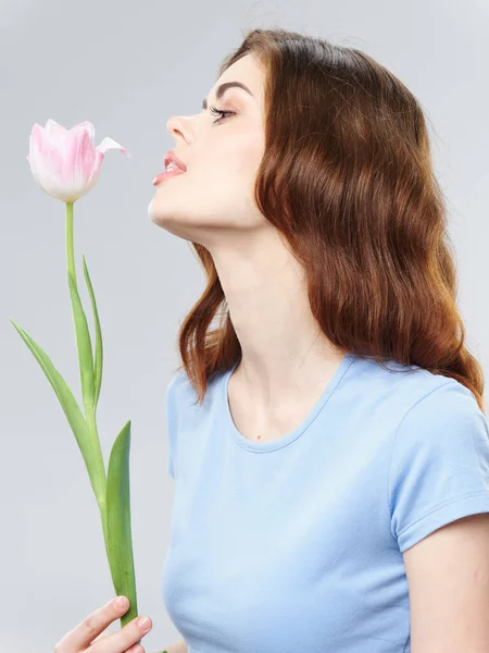 Mooie vrouw met roze bloem op een grijze achtergrond — Stockfoto