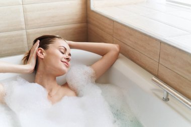 Mutlu kadın banyoda dinlenmekten ve beyaz köpükten hoşlanır. 