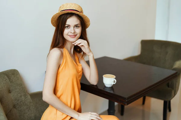 Charming girl in a dress in a cafe and a hat — Stock Photo, Image