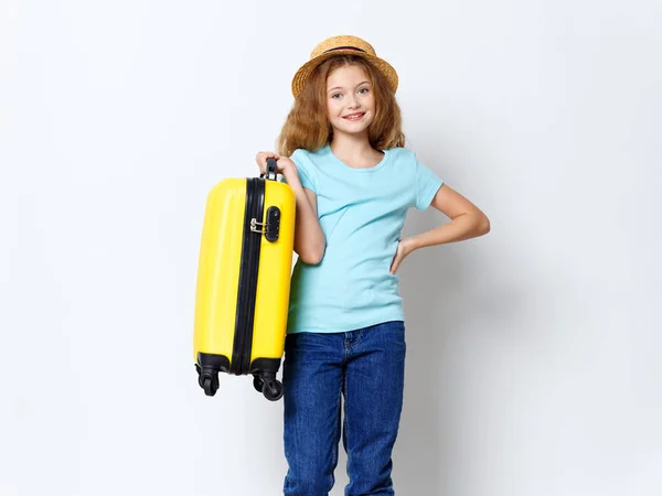 Glückliches Mädchen mit gelbem Koffer hält seine Hand am Gürtel und lächelt — Stockfoto