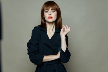 Gri arka planda, siyah ceketli ve kırmızı dudaklı bir kadın.