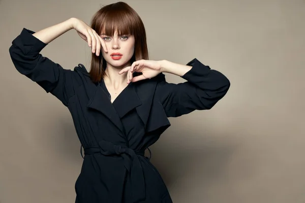 Una deliziosa modella donna in un cappotto nero si tocca il viso — Foto Stock