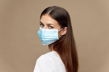 Yüzü maskeli çekici bir kadın. Bej arka planda alerji kirliliği. 