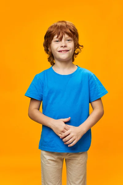 微笑的红头发男孩前视蓝色T恤黄色背景 — 图库照片