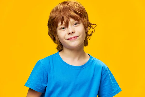 Sonriente pelirroja chico primer plano azul camiseta amarillo fondo — Foto de Stock