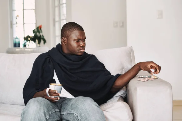 Таблетки на диване человек проблемы со здоровьем и чашку — стоковое фото