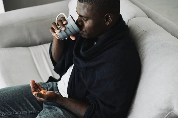 Африканский мужчина с таблетками и чашкой воды — стоковое фото