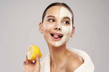 Yüzünde beyaz bir maske ve elinde bir dilim limon.