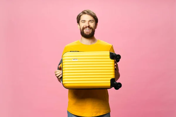 Koffer in de handen van een gelukkige man op een roze achtergrond — Stockfoto
