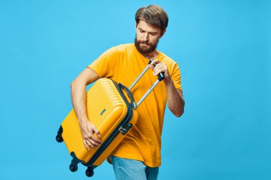 Mavi arka planda bavulu olan bir turist 