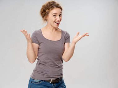 Gri tişörtlü ve kot pantolonlu yaşlı kadın elleriyle el kol hareketi yapıyor.