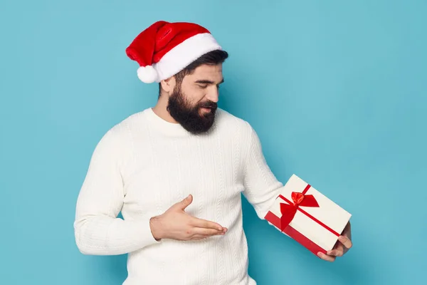 Los regalos en las manos de los hombres sobre el fondo azul y el sombrero de fiesta de Navidad — Foto de Stock