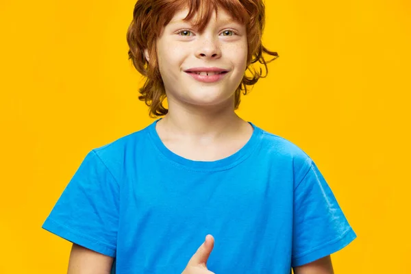 Happy boy close-up cropped view blue t-shirt yellow background red hair — Stock Photo, Image