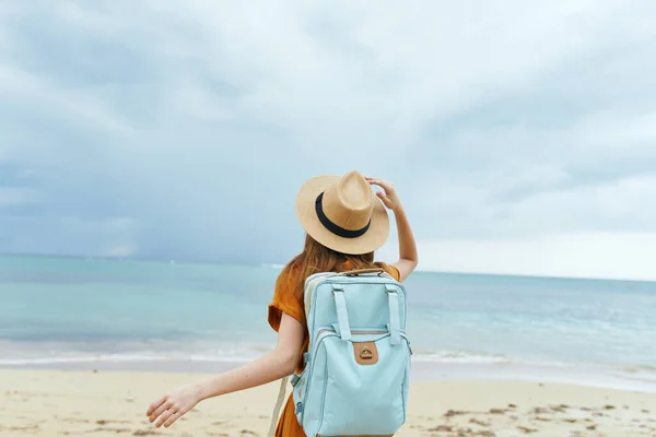 Kvinna turist blå ryggsäck på baksidan hatt stranden — Stockfoto