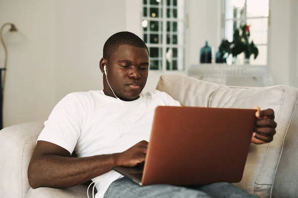 Un homme se trouve sur le canapé avec un ordinateur portable dans la technologie casque — Photo