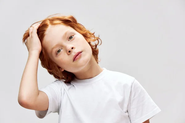 Un adolescente con el pelo rojo sostiene una mano en su cabeza camiseta blanca —  Fotos de Stock
