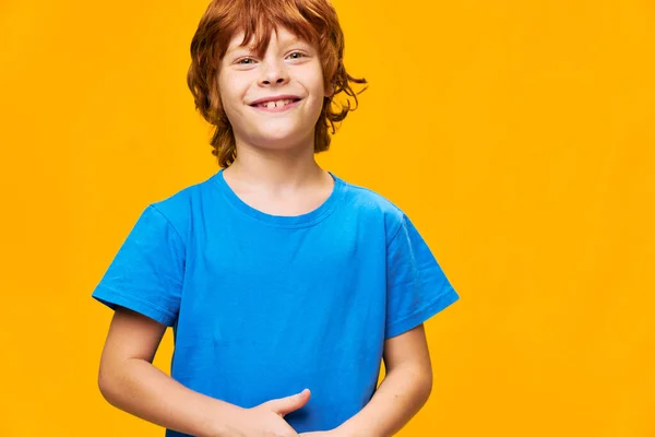 Vermelho de cabelos felizes menino no fundo amarelo em azul t-shirt — Fotografia de Stock