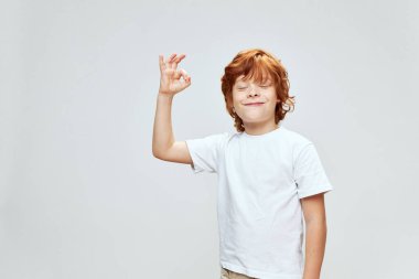 Neşeli, kızıl saçlı, el hareketleriyle gülümseyen, gözleri kapalı, beyaz tişört stüdyosu 