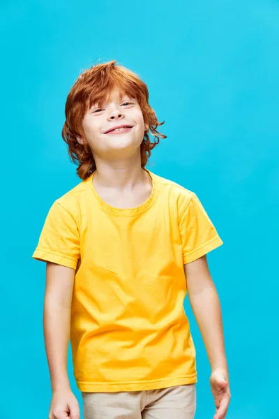 Sproeten roodharig kind in geel t-shirt glimlachend op blauwe achtergrond — Stockfoto