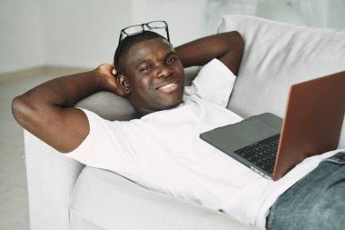 Adam dizüstü bilgisayarda yatıyor. Afrikalı gibi görünüyor. Teknoloji bürosu işi. 