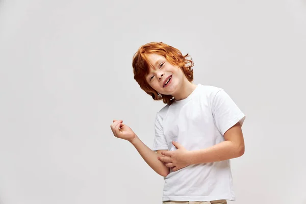 Alegre chico pelirrojo inclinando su cabeza a un lado blanco camiseta infancia —  Fotos de Stock