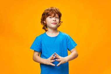 Kızıl saçlı yakışıklı çocuk mavi tişört sarı arka plan 