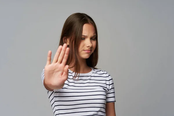 girl doing stop gesture on gray background sad face