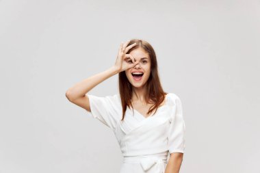 Beyaz elbiseli neşeli bir kadın gülümsüyor. 