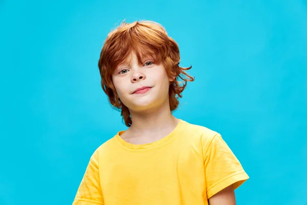 Enfant roux en T-shirt jaune sur fond bleu plié sur le côté — Photo