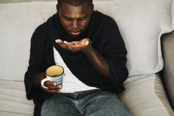 Afrikaner mit Tabletten in der Hand auf Couch und Tasse — Stockfoto