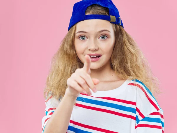 Chica muestra un dedo a la cámara y una gorra azul —  Fotos de Stock