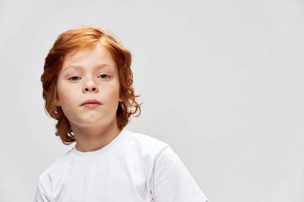 Lindo chico de pelo rojo con pecas en la cara con camiseta blanca gris aislado fondo — Foto de Stock