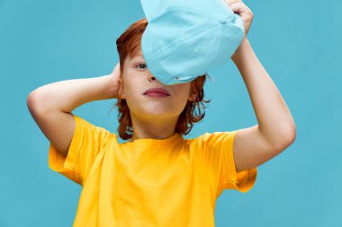 Kızıl saçlı çocuk yüzünün önünde elinde bir şapka tutuyordu. 