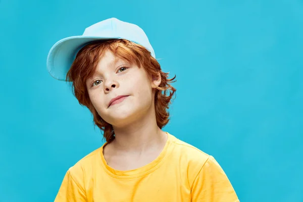 Rödhårig pojke på en blå bakgrund böjd till sidan beskuren vy — Stockfoto