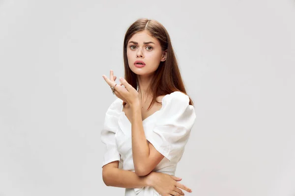 Femme émotionnelle regardant droite robe blanche studio fond gris — Photo