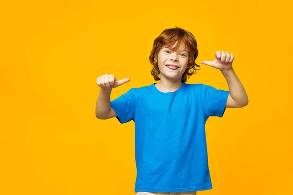 Wesoły rudowłosy chłopiec pokazuje język uśmiech gesty ręce emocje żółty tło Kopiuj przestrzeń — Zdjęcie stockowe
