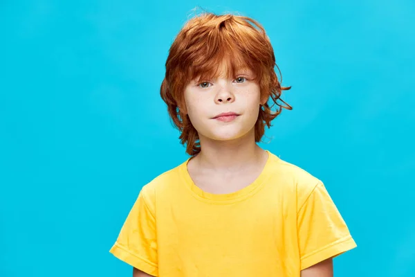 Vackra barn på en blå bakgrund i en gul t-shirt säker look — Stockfoto