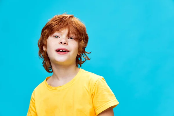 Rött hår pojke i en gul T-shirt på en blå bakgrund närbild — Stockfoto