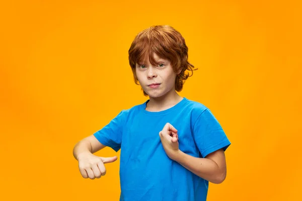 A boy with freckles shows his thumb to himself and a blue t-shirt — Stock Photo, Image