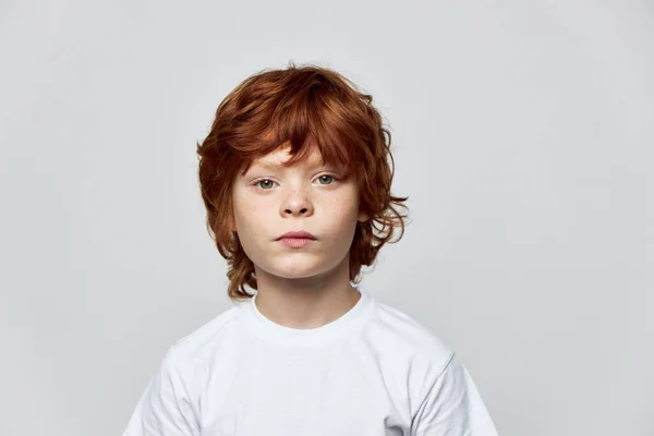 Retrato de un chico pelirrojo sobre un fondo gris vista recortada de una camiseta blanca —  Fotos de Stock