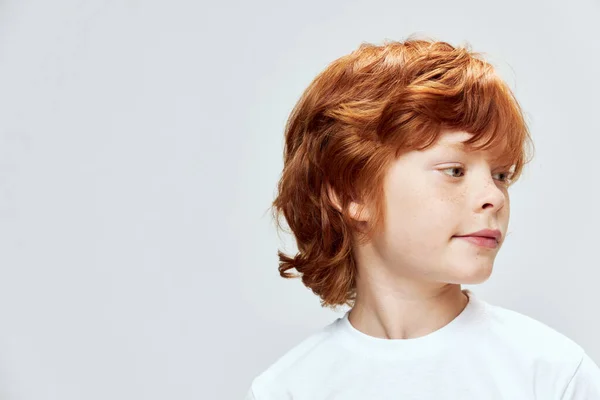 Roodharige jongen gezicht close-up hoofd gedraaid aan de zijkant close-up grijze achtergrond — Stockfoto