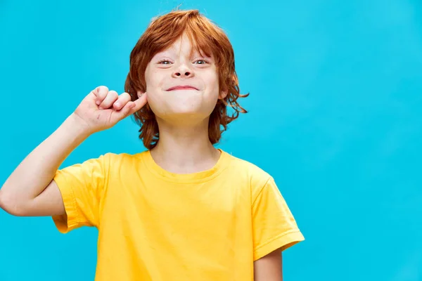 Expressivo ruiva criança segurando o dedo perto do rosto e enérgico menino retrato — Fotografia de Stock