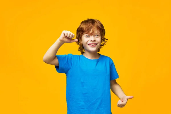 Menino alegre com gestos de cabelo vermelho com as mãos gesto positivo sorriso azul t-shirt estúdio close-up Espaço Copiar . — Fotografia de Stock