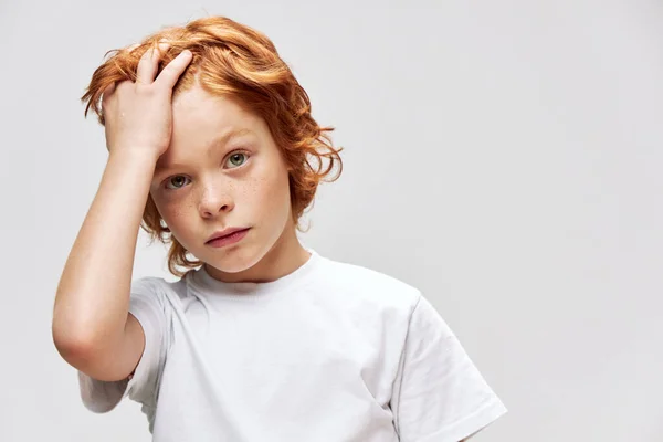 Κοκκινομάλλικο αγόρι που κρατάει φακίδες μαλλιών στο πρόσωπό του λευκό μπλουζάκι — Φωτογραφία Αρχείου