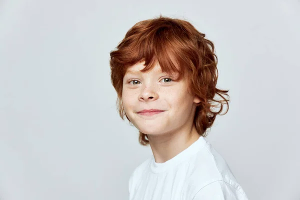 Menino de cabelos vermelhos em um fundo cinza sorriso branco t-shirt cortada — Fotografia de Stock