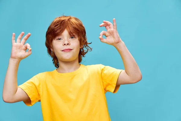 Červenovlasé dítě ve žlutém tričku ukazuje pozitivní gesto — Stock fotografie
