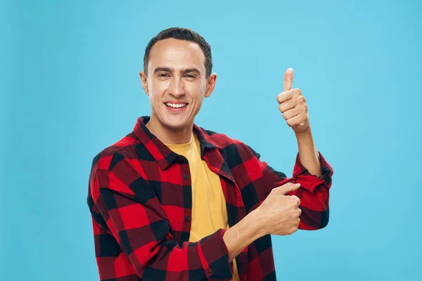 Een man in een geruit shirt toont met zijn hand een duim omhoog plezier — Stockfoto