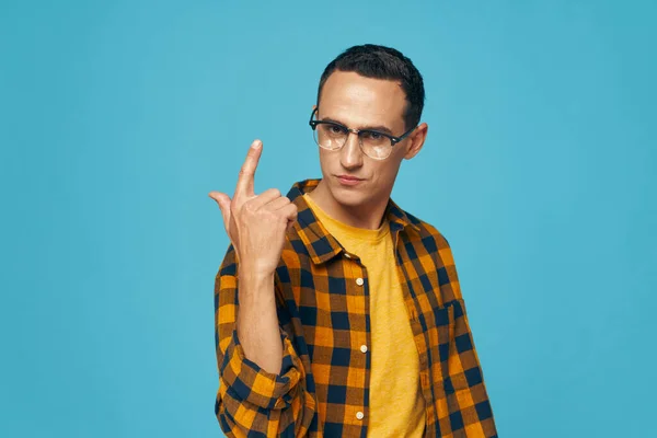 Un hombre con una camisa a cuadros está haciendo gestos con las manos usando gafas. Estilo de vida Copiar espacio — Foto de Stock